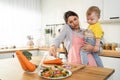 Caucasian busy mother doing housework with baby boy toddler in kitchen. Beautiful single mom use phone call for work and cook Royalty Free Stock Photo