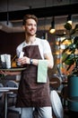 Smiling industrious waiter with napkin working in cafe