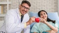 Caucasian cardiology doctor and asian patient holding heart shape ball together in concept of heart attack prevention campaign