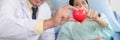 Caucasian cardiology doctor and asian patient holding heart shape ball together in concept of heart attack prevention campaign