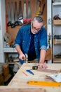 Caucasian carpenter man use hammer to hit nail on wood table for working in workplace Royalty Free Stock Photo