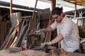 Caucasian carpenter wearing a safety goggle and cutting wood on a table saw in a carpentry shop