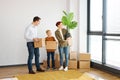 Caucasian cheerful mother, father and little son with stuff in boxes moving to new home Royalty Free Stock Photo