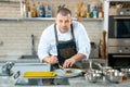 Caucasian chef putting food on a plate in a restaurant kitchen.