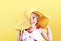 Caucasian child girl in hat on yellow empty space background,summer vocation concept