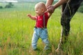 Caucasian child learns to walk. Mom holds his hand.