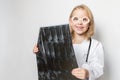 Caucasian child, little doctor smiling and holding x-ray film, standing on neutral background Royalty Free Stock Photo