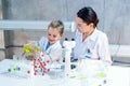 A Caucasian child and an mother are conducting a science experiment together, mixing colorful liquids in a laboratory setting,