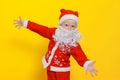 Caucasian child in New Year`s Santa Claus costume spread his arms in different directions showing a gesture that he wants to hug