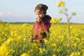 Caucasian child outdoors in the blooming rape field smelling a flower Royalty Free Stock Photo