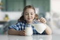 Caucasian child pouring milk from jar to glass. Toddler have a meal of dairy products.Little girl happy face portrait at kitchen Royalty Free Stock Photo