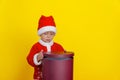 Caucasian Child in Santa Claus Clothes Opens Red Round Gift Box. Royalty Free Stock Photo