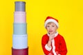 Caucasian child sits near a tower of round gift boxes, holds a finger to his mouth, urging with this gesture that it is a secret Royalty Free Stock Photo