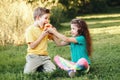 Caucasian children boy and girl siblings sitting together sharing apple. Two kids brother and sister eating sweet fruit in a park