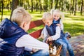 Caucasian children play chess on wooden chessboard in park bench. Brothers and sister big friendly active mental family spend time Royalty Free Stock Photo