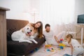 Children playing together on floor while young parents relaxing at home Royalty Free Stock Photo