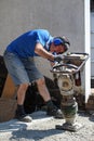 Caucasian construction worker compacting soil using a tamping rammer machine