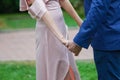 Caucasian couple, bride in ivory satin dress and groom in dark blue suit holding hands