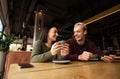 Caucasian couple drinks coffee in cafe. Brunette woman warms her hands on the cup she holds in her hands and smiles to