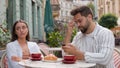 Caucasian couple eat breakfast in city cafe outdoors addicted busy man boyfriend using mobile phone ignoring upset woman Royalty Free Stock Photo