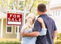 Caucasian Couple Facing Front of Sold Real Estate Sign and House