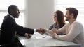 Caucasian couple handshake biracial male agent greeting Royalty Free Stock Photo