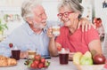 Caucasian couple having fun during breakfast at home. Senior people relaxed and happy, holding a coffee and milk cup Royalty Free Stock Photo