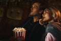 Caucasian couple lovers in romance moment together watching love story movie in theater with bucket of popcorn