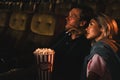 Caucasian couple lovers in romance moment together watching love story movie in theater with bucket of popcorn Royalty Free Stock Photo