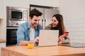 Caucasian couple smiling using a laptop and a credit card to buy on internet. Young husband and happy wife paying a Royalty Free Stock Photo