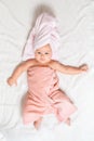 A caucasian cute baby wrapped in a pink towel lying on a white sheet. View from the top. Baby after bathing Royalty Free Stock Photo