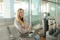 Caucasian cute girl sitting in waiting room with laptop near valise. Royalty Free Stock Photo