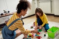 Have fun. Caucasian cute little girl spending time with african american baby sitter. They are playing with construction Royalty Free Stock Photo
