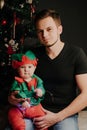 Caucasian dad with a beard with a little boy son in his arms on the background of a Christmas tree Royalty Free Stock Photo