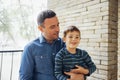 Caucasian dad hugging his cute smiling son. Young man communicates with a little boy on the porch of the house Royalty Free Stock Photo