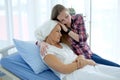 Caucasian daughter is Holding hands Elderly Mother in white headscarf is laying on bed in hospital after chemotherapy because she Royalty Free Stock Photo