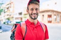 Caucasian delivery man wearing red uniform and delivery backpack smilly happy outdoors Royalty Free Stock Photo