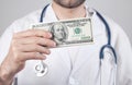 Caucasian doctor showing dollar banknotes