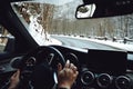 Caucasian driver holding hands on steering wheel and driving on mountain road Royalty Free Stock Photo