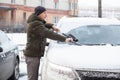 Caucasian driver removing snow under rubber wipers of his suv at winter time