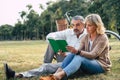 Caucasian elderly couple relaxing and sitting at the park reading the book and spending quality time together, happy marriage Royalty Free Stock Photo