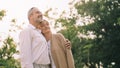 Caucasian elderly couple is standing, holds each other and smiling upward enjoy spending time together with happiness, a happily