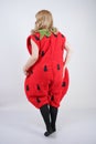 Caucasian emotive blonde girl in a huge plush suit of red strawberry on a white background in the Studio