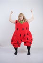 Caucasian emotive blonde girl in a huge plush suit of red strawberry on a white background in the Studio