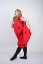 Caucasian emotive blonde girl in a huge plush suit of red strawberry on a white background in the Studio