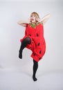 Caucasian emotive blonde girl in a huge plush suit of red strawberry on a white background in the Studio