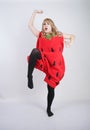 Caucasian emotive blonde girl in a huge plush suit of red strawberry on a white background in the Studio