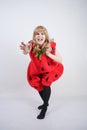 Caucasian emotive blonde girl in a huge plush suit of red strawberry on a white background in the Studio