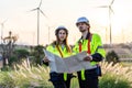 Caucasian engineer man discuss together with co-worker woman hold blueprint and stay in front of row of windmill or wind turbine Royalty Free Stock Photo