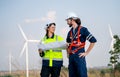 Caucasian engineer man discuss together with co-worker woman hold drawing paper and stay in front of row of windmill or wind Royalty Free Stock Photo